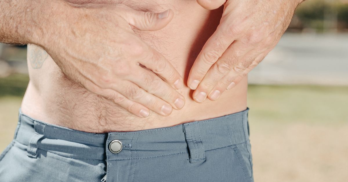 A person holding their abdomen, indicating possible discomfort or injury.