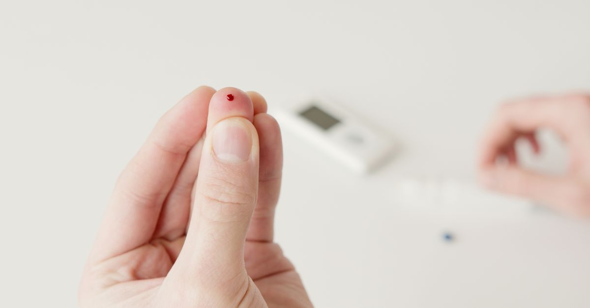 A close-up view of a hand with a blood drop, illustrating a diabetic blood sugar test.