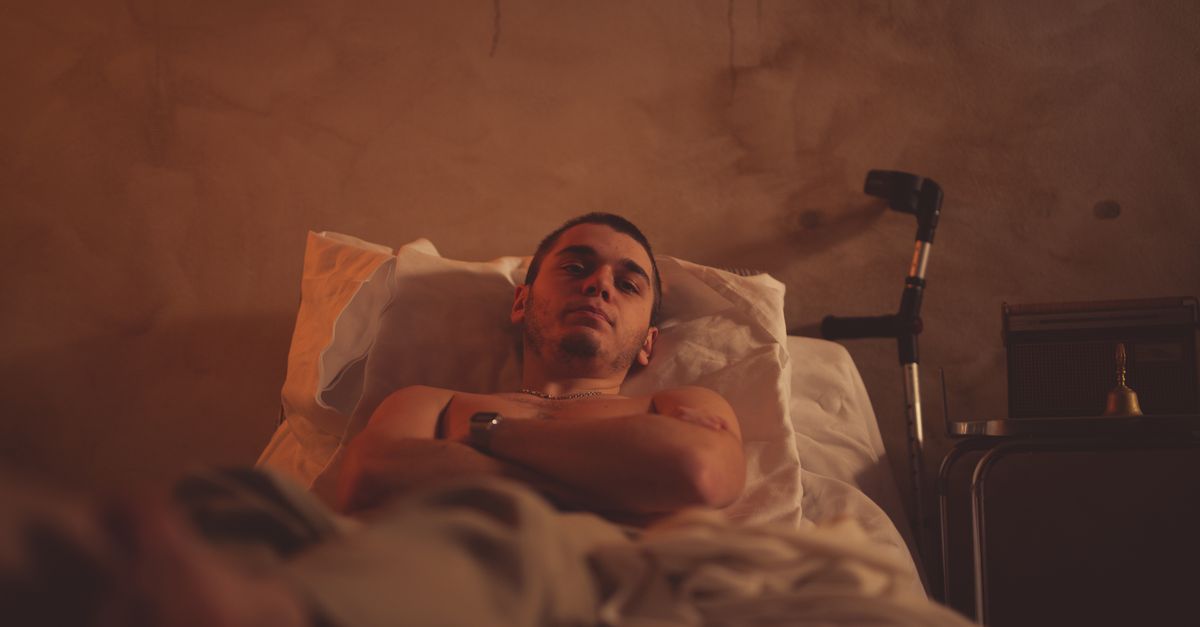 A young man with crutches lying in bed, possibly recovering from an injury.