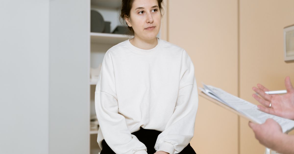 Adult woman sitting attentively during a medical consultation inside a clinic.