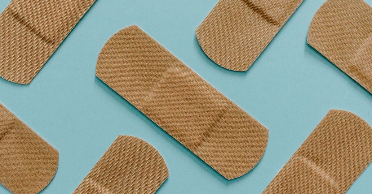 A minimalist flat lay of adhesive bandages on a blue background, perfect for health and treatment themes.