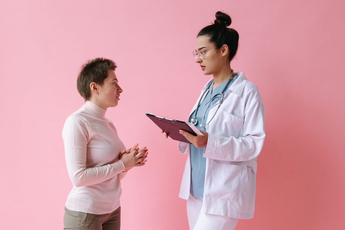 A woman consulting with a doctor who is holding a clipboard.
