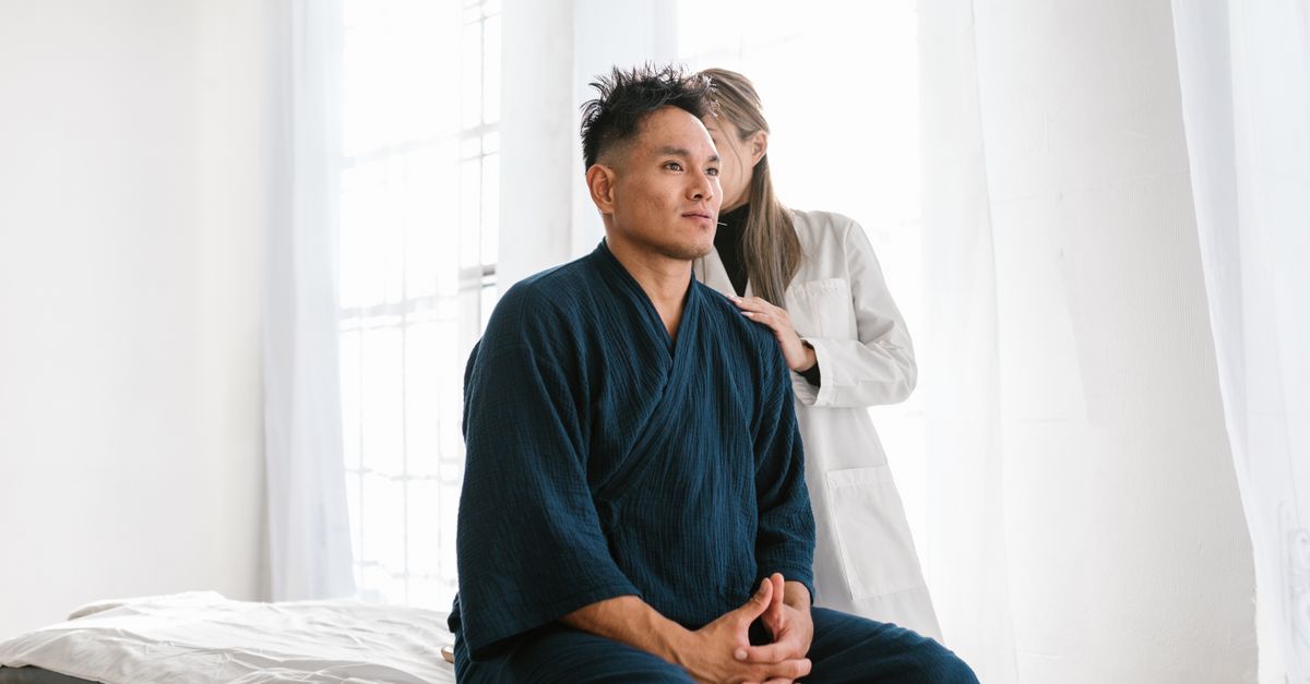 A doctor examines a patient seated on a treatment table in a medical facility.