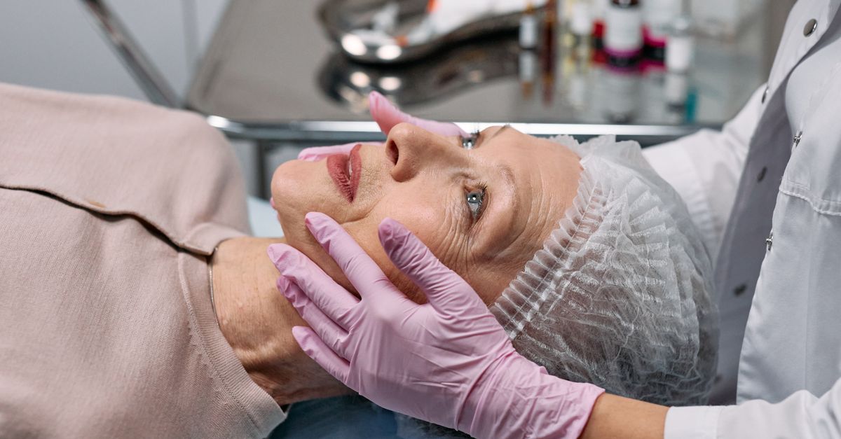 Medical professional examining a senior woman's face in a clinical setting.
