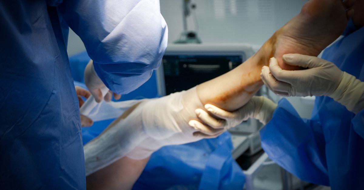 Close-up of doctors treating a patient's leg in a surgical room setting.