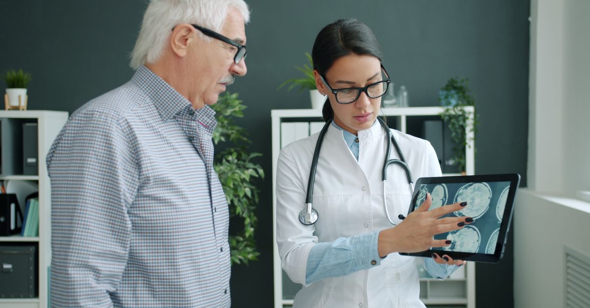 Medical professional reviewing brain scans with an elderly man in a clinic.