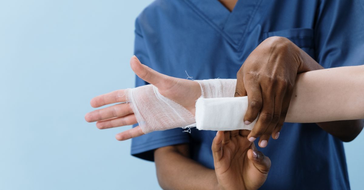 Detailed image of a man wrapping his hand with black bandages in a gym setting.